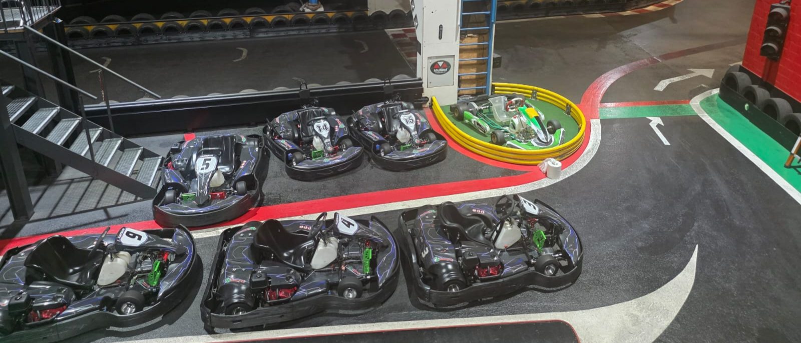 Sechs Karts vor Start und Ziel aufgereiht, daneben ein Rennchassis