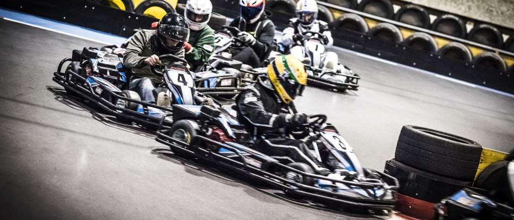 Fünf Karts dicht hintereinander in einer Kurve, alle Fahrer mit Helm